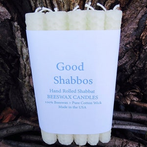 May include: A package of hand-rolled beeswax Shabbat candles with a white label that reads "Good Shabbos", "Hand Rolled Shabbat BEESWAX CANDLES", "100% Beeswax > Pure Cotton Wick", and "Made in the USA".