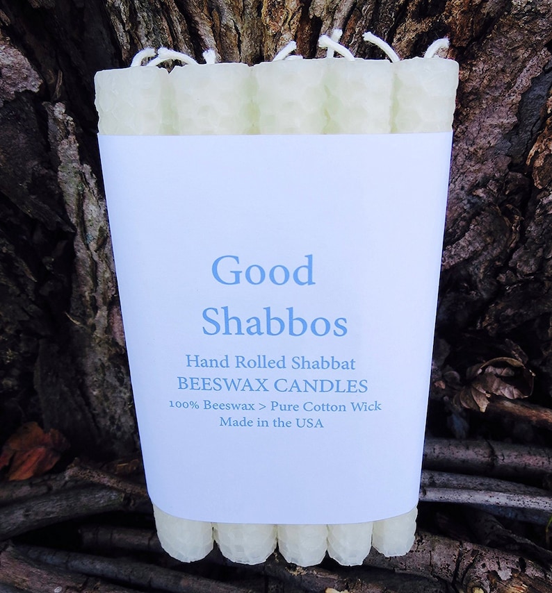 May include: A package of hand-rolled beeswax Shabbat candles with a white label that reads "Good Shabbos", "Hand Rolled Shabbat BEESWAX CANDLES", "100% Beeswax > Pure Cotton Wick", and "Made in the USA".