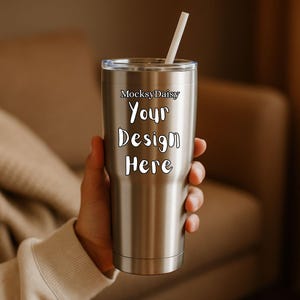 Könnte beinhalten: Ein Edelstahlbecher mit einem transparenten Deckel und einem weißen Strohhalm. Der Becher trägt den weißen Text "MocksyDaisy Your Design Here". Der Becher ist zylindrisch und scheint isoliert zu sein.