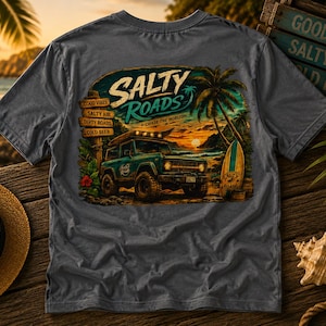 May include: A charcoal gray t-shirt featuring a graphic print of a teal off-road vehicle with a surfboard on its roof. The design includes palm trees, a sunset, and text that reads Salty Roads, Chase The Horizon, Good Vibes, Salty Air, Dirty Roads, Cold Beer.