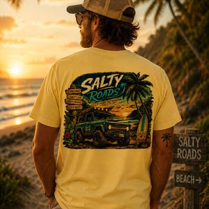 May include: A pale yellow t-shirt featuring a graphic on the back with a dark green off-road vehicle, a surfboard, a palm tree, and a wooden signpost. The text reads Salty Roads, Good Vibes, Salty Air, Dirty Roads, Cold Beer, and Chase the Horizon.