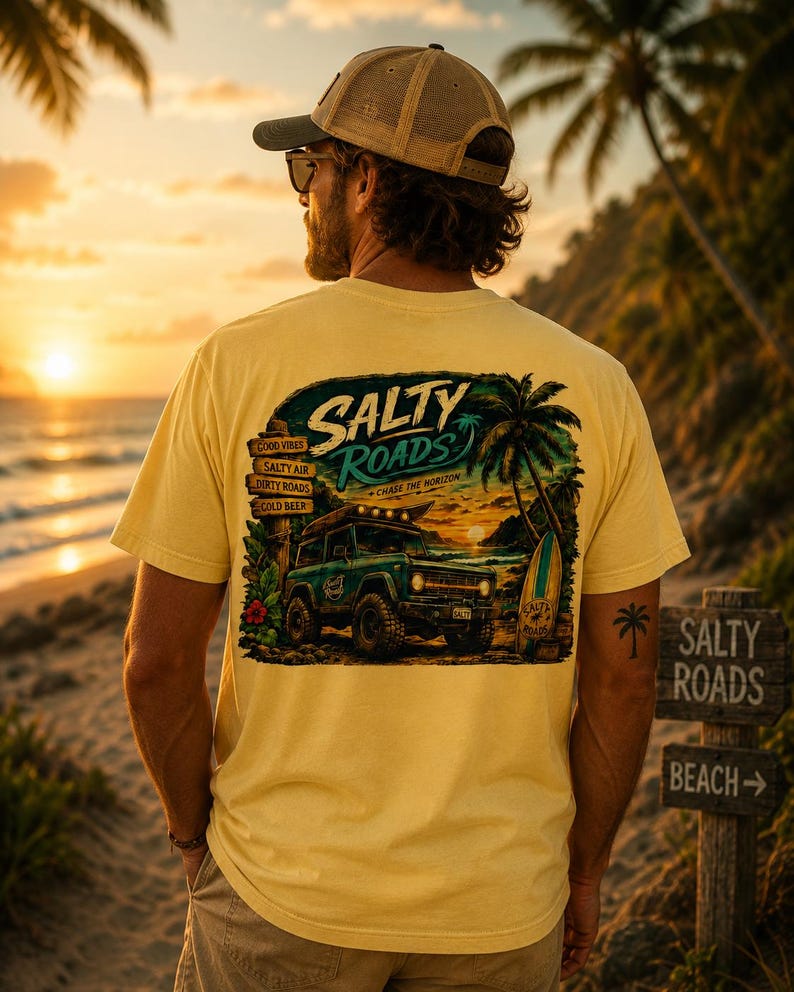 May include: A pale yellow t-shirt featuring a graphic on the back with a dark green off-road vehicle, a surfboard, a palm tree, and a wooden signpost. The text reads Salty Roads, Good Vibes, Salty Air, Dirty Roads, Cold Beer, and Chase the Horizon.