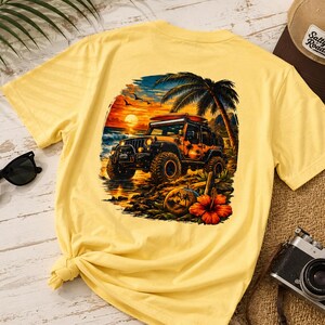 Może przedstawiać: Jasnoż&oacute;łty t-shirt z nadrukiem graficznym przedstawiającym samoch&oacute;d terenowy zaparkowany na plaży o zachodzie słońca. Wz&oacute;r zawiera palmę, deskę surfingową na dachu oraz duży czerwony kwiat hibiskusa na pierwszym planie w żywych kolorach.