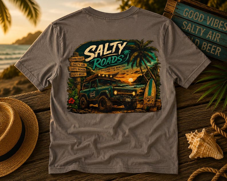 May include: A grey t-shirt featuring a graphic print of a teal off-road vehicle on a beach at sunset. The text reads Salty Roads, Chase the Horizon, Good Vibes, Salty Air, Dirty Roads, and Cold Beer. A palm tree and surfboard are also visible.