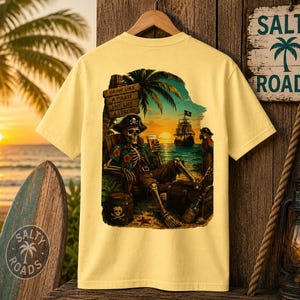 K&ouml;nnte beinhalten: Ein hellgelbes T-Shirt mit einem Grafikdruck auf der R&uuml;ckseite, der ein Piratenskelett mit Blumenhemd und Hut zeigt, das bei Sonnenuntergang am Strand sitzt. Die Grafik enth&auml;lt ein Holzschild mit dem Text, Drink Like A Pirate Live Like A Legend.
