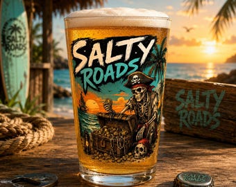 Könnte beinhalten: Ein klares Glas gefüllt mit goldenem Bier und weißem Schaum, verziert mit einer Grafik eines Piratenskeletts mit Hut, das eine Goldmünze an einer Schatztruhe hält, mit dem Text SALTY ROADS in fetten schwarzen und türkisfarbenen Buchstaben.