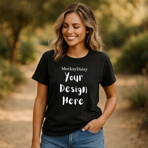 Könnte beinhalten: Schwarzes T-Shirt mit dem weißen Text "MocksyDaisy Your Design Here". Das T-Shirt hat einen Rundhalsausschnitt und wird von einer Person getragen. Die Person lächelt und trägt eine blaue Jeans.