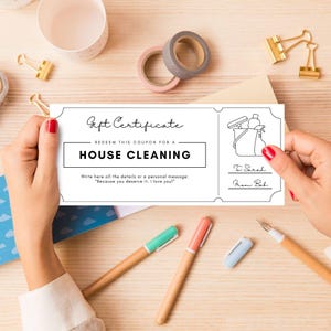 May include: A white gift certificate for house cleaning, held by a person with red nail polish. The certificate reads "Gift Certificate" and "House Cleaning." It includes a cleaning supplies illustration and a handwritten note.