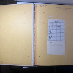 May include: Open vintage book with yellowed pages. The left page is blank, while the right page has a library card and a label that reads "THE GOLDEN BOOK OF POETRY". The book is from Tavares Elementary School Library, Tavares, Florida.