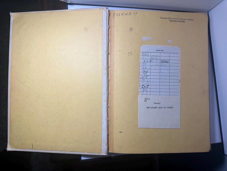 May include: Open vintage book with yellowed pages. The left page is blank, while the right page has a library card and a label that reads "THE GOLDEN BOOK OF POETRY". The book is from Tavares Elementary School Library, Tavares, Florida.