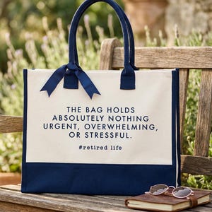 Tote bag design featuring a humorous quote reading the bag holds absolutely nothing urgent overwhelming or stressful displayed in bold uppercase lettering with a clean and centered layout; includes a small retired life phrase underneath for added personality; designed with a minimal modern style that highlights the text clearly; ideal for retirement gifts, everyday use, or carrying essentials with a lighthearted and relaxed vibe