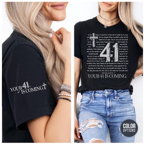 May include: Black t-shirts with the text "YOUR 41 IS COMING" and a cross graphic. One shirt has the text on the sleeve, the other has a detailed biblical passage and "41" on the front. The model is wearing blue jeans.