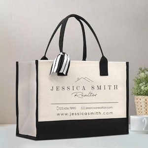 May include: A rectangular canvas tote bag with black trim and black handles. A black and white striped ribbon is tied to one handle. The bag features the text JESSICA SMITH REALTOR, a house icon, a phone number, an email address, and a website URL.
