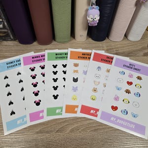Może przedstawiać: Zestaw arkuszy naklejek z różnymi wzorami. Arkusze zawierają postacie z Disney'a, Minnie Mouse, Mickey Mouse, Aniteez, SKZOO i BT21. Każdy arkusz ma kolorową obwódkę i tekst "STICKER SHEET" lub nazwę postaci.