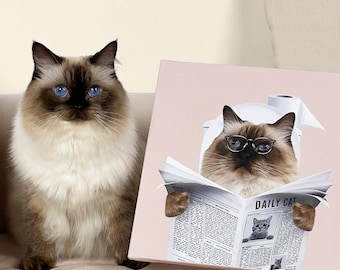 May include: A fluffy, light brown and white cat with striking blue eyes sits next to a canvas print. The print features a cat wearing glasses and reading a newspaper titled "DAILY CAT". The cat in the print is wearing a toilet paper hat.