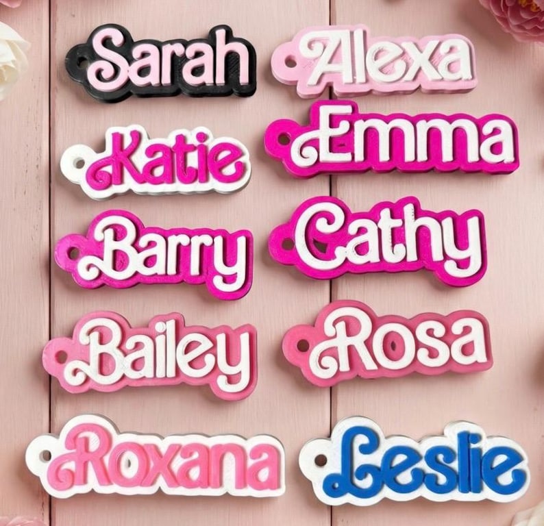 Może przedstawiać: Kolekcja imiennik&oacute;w w r&oacute;żnych kolorach. Nazwy to "Sarah", "Alexa", "Katie", "Emma", "Barry", "Cathy", "Bailey", "Rosa", "Roxana" i "Leslie". Każdy znacznik ma unikalną kolorystykę, z nazwami w kolorze białym lub niebieskim i kolorową obw&oacute;dką.