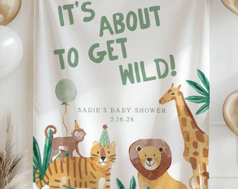 May include: A white banner with the text "IT'S ABOUT TO GET WILD!" in green, featuring illustrations of a tiger, lion, giraffe, and monkey. Gold and white balloons and a banner of gold triangles decorate the background. "Sadie's Baby Shower 5.16.26" is also printed.