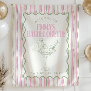 Könnte beinhalten: Ein Partybanner mit rosa und weißen Streifen, mit dem Text "WELCOME TO EMMA'S BACHELORETTE" in Rosa. Eine Martini-Glas-Illustration mit einer Braut befindet sich in der Mitte. Goldene und weiße Luftballons und goldene Dreiecks-Wimpelketten schmücken den Hintergrund.