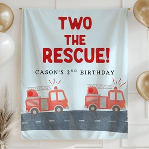 May include: A light blue birthday banner with the text "TWO THE RESCUE!" in red. Below the text is "CASON'S 2ND BIRTHDAY". Two red fire trucks are printed at the bottom. Gold and white balloons are on either side.