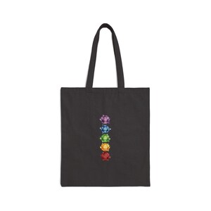 May include: Black tote bag with a vertical arrangement of colourful, gem-like designs. The designs are in a row, with purple, blue, green, yellow, and red colours. The bag has two black handles.