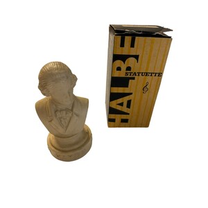 May include: A white plaster bust of a man with a base. The bust is in a box that says "Halbe Statuette" with a treble clef symbol.