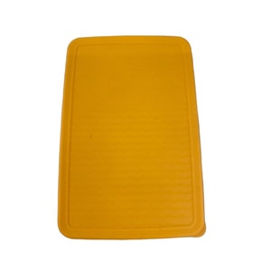 Puede incluir: Una tabla de cortar de plástico amarilla con una superficie texturizada.