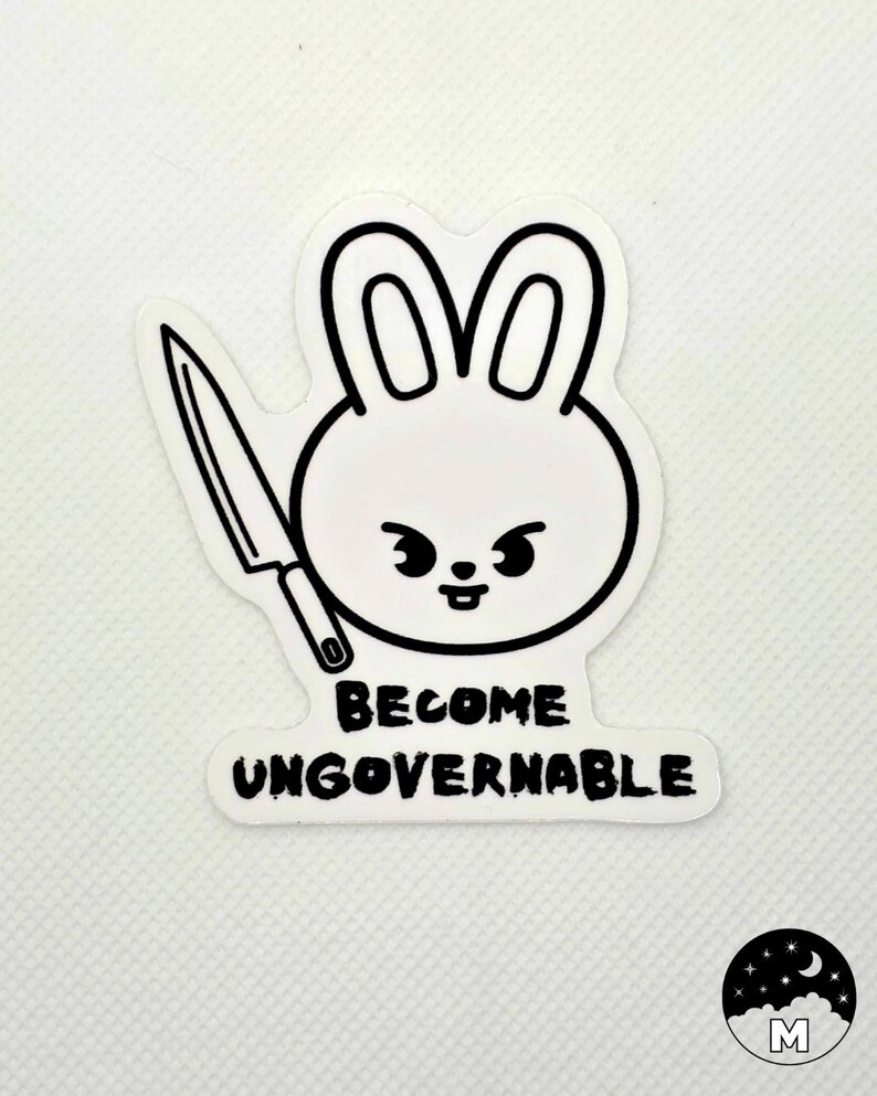 May include: A white sticker featuring a cartoon rabbit head with a knife and the words "BECOME UNGOVERNABLE" in black. The rabbit has a stern expression. A small logo with a moon and stars is in the bottom right corner.