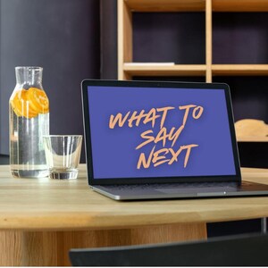 May include: A laptop displays the text "WHAT TO SAY NEXT" in orange on a blue screen. A clear glass bottle with orange slices and a small glass sit on a wooden table. A wooden shelf is in the background.