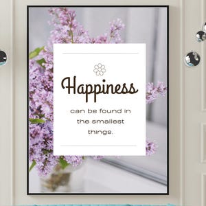 May include: A framed print with the word "Happiness" and the phrase "can be found in the smallest things" over a floral background. A turquoise sofa and two white and gold tables are in front of the print.