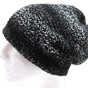 May include: A black, white, and gray knit beanie hat. The hat is made of a thick, textured yarn and has a slouchy fit. The color pattern is a mix of black, white, and gray, creating a marbled effect.