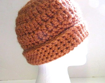 May include: A crocheted beanie hat in a warm terracotta colour. The hat has a wide brim and is made with a textured stitch.