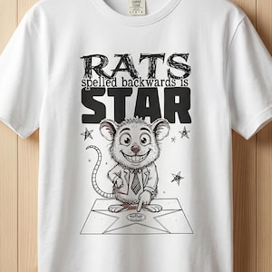 May include: White t-shirt with a graphic of a smiling cartoon mouse on a star, with the text "RATS spelled backwards is STAR". The design is in black and white.