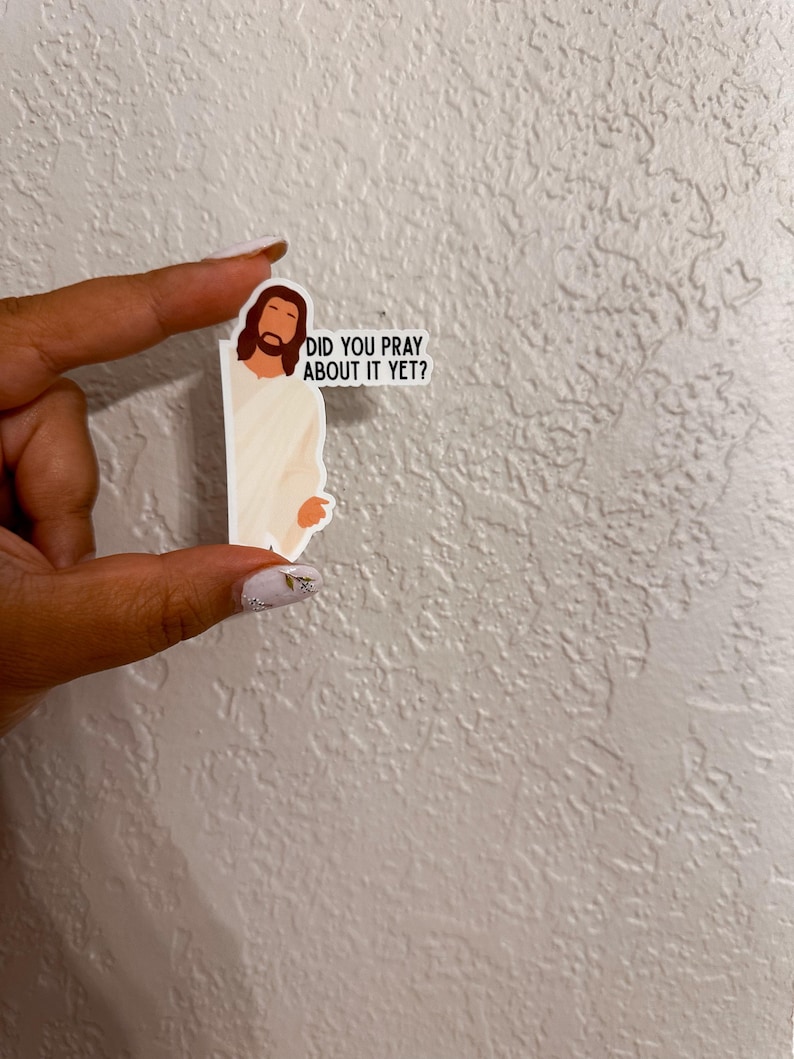 Op de afbeelding: Een sticker met een cartoonillustratie van Jezus met bruin haar en een baard, gekleed in een wit gewaad. De sticker bevat de tekst "DID YOU PRAY ABOUT IT YET?" in zwarte letters.