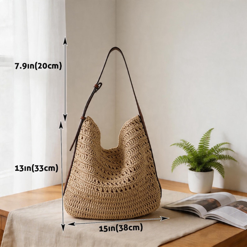 Op de afbeelding: Een beige geweven draagtas met bruine leren bandjes. De tas is 33 cm hoog, 38 cm breed en 20 cm diep. De tas staat op een houten tafel.