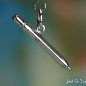 May include: Silver charm in the shape of a pen, with a loop at the top for attaching to a bracelet or necklace.