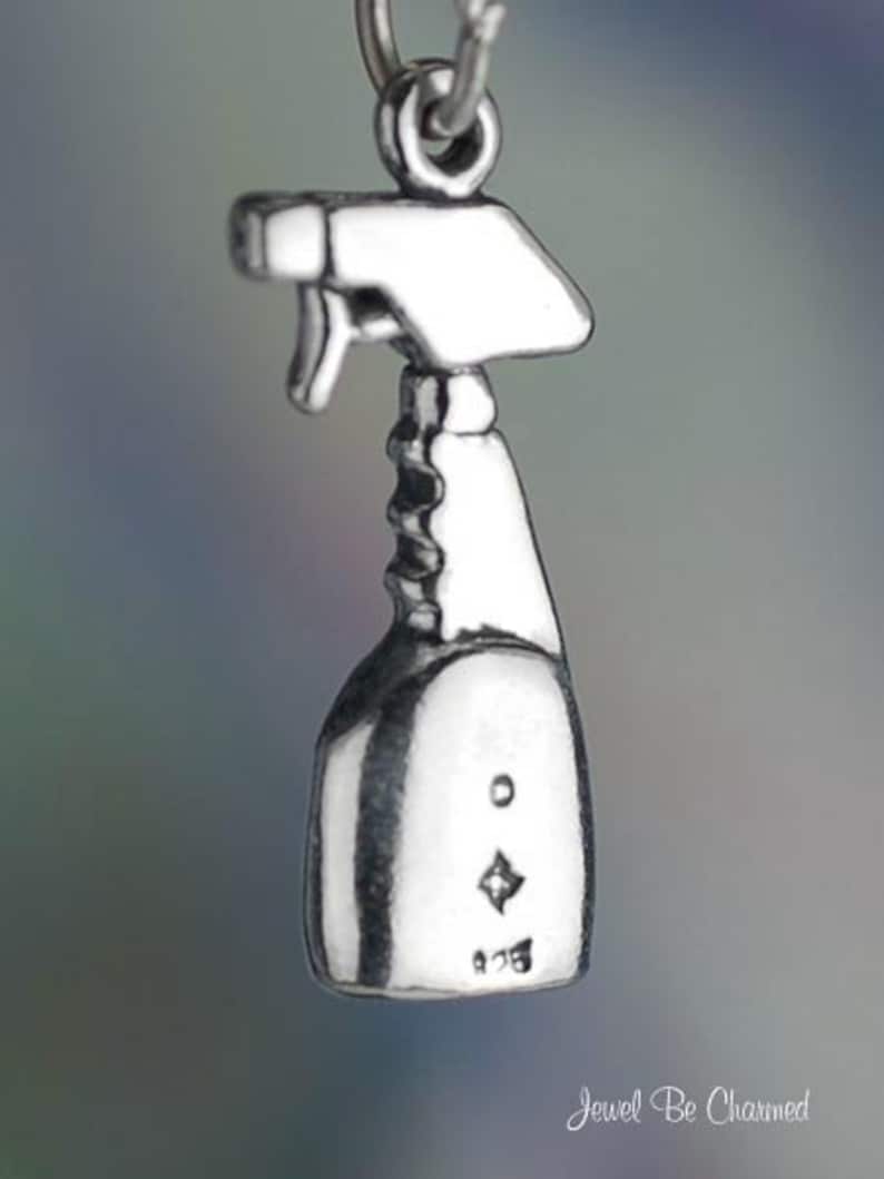 May include: Silver charm in the shape of a spray bottle. The charm has a detailed design and is perfect for adding a touch of whimsy to any jewelry piece.