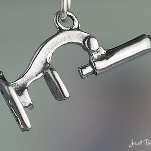 May include: A silver charm in the shape of a microscope. The charm is detailed and has a realistic design.