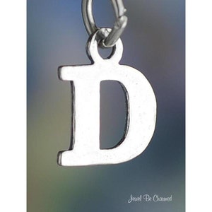 May include: Silver charm in the shape of the letter D. The charm is a simple, classic design.