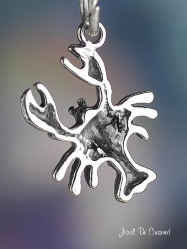 May include: Silver charm in the shape of a crab. The charm is detailed and has a textured surface.