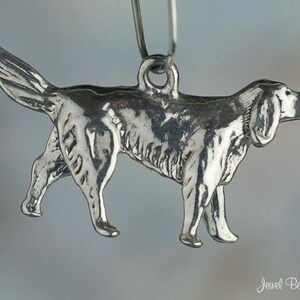 May include: A silver charm in the shape of a dog. The charm is detailed and has a realistic look. It is a great addition to any charm bracelet.