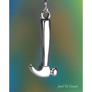 May include: A silver-colored hammer pendant with a rounded head and a long handle. The hammer is suspended from a small loop. The background is a gradient of blue, green, and yellow.