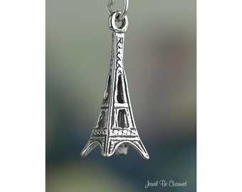 May include: Silver charm in the shape of the Eiffel Tower. The charm is detailed with intricate lines and features a loop at the top for attaching to a bracelet or necklace.