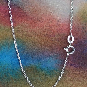 May include: A silver chain necklace with a lobster clasp closure. The chain is on a colorful background.