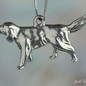 May include: A silver charm in the shape of a dog, with a detailed design and a smooth finish. The charm is hanging from a silver loop.