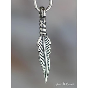 May include: A silver feather charm with a twisted detail at the top. The charm is designed to be added to a necklace or bracelet.