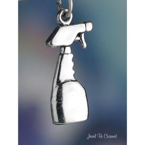 May include: Silver charm in the shape of a spray bottle. The charm is detailed and has a realistic design.