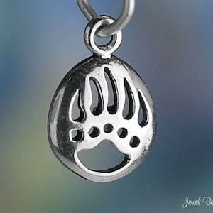May include: A silver charm in the shape of a bear paw print. The charm is detailed with five claws and a textured surface.