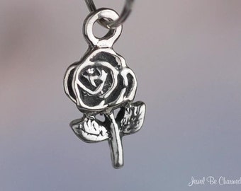 May include: A silver charm in the shape of a rose. The rose has a detailed design with petals and a stem.