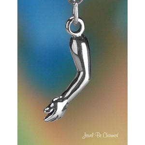May include: A silver charm in the shape of an arm, with the hand outstretched. The charm is designed to be attached to a bracelet or necklace.