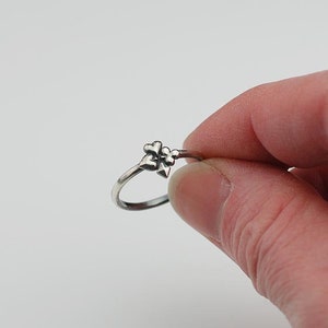 May include: A silver ring with a cluster of three small, heart-shaped designs.